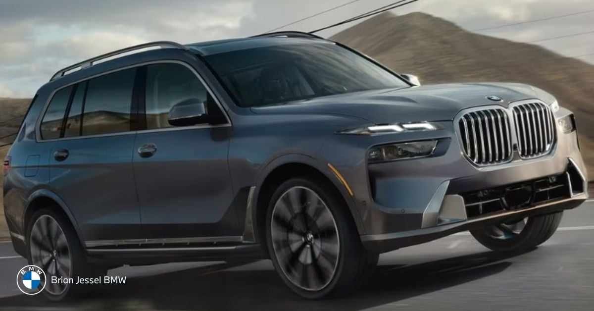A grey BMW X7 driving on a winding mountain road.