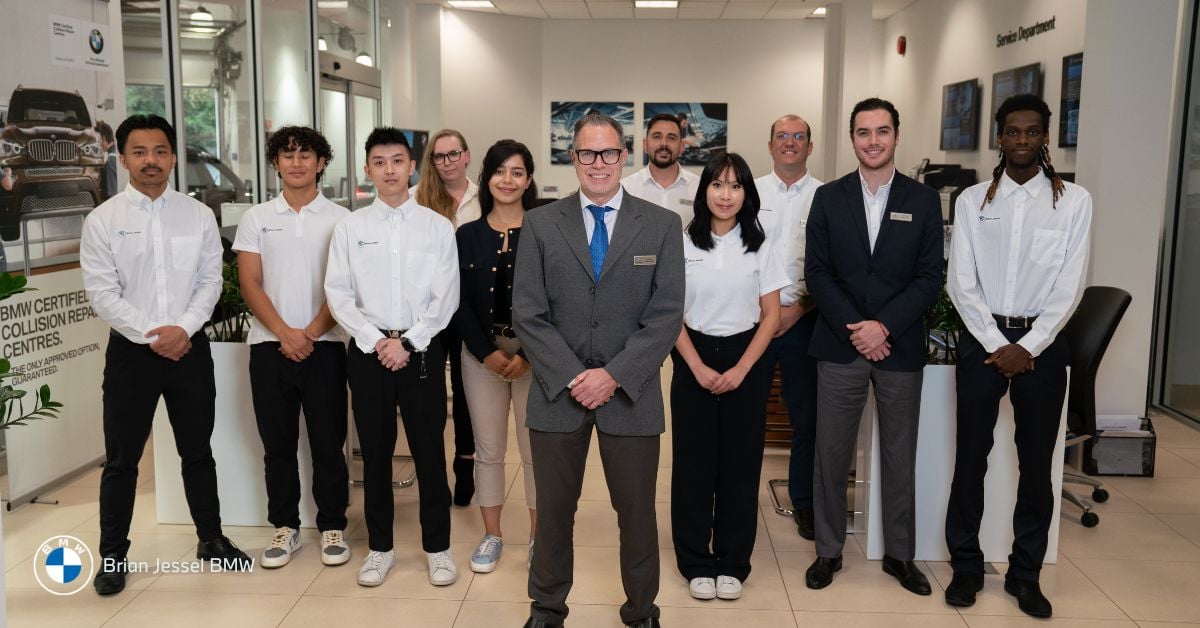 A group of staff members at Brian Jessel BMW standing together inside the dealership.