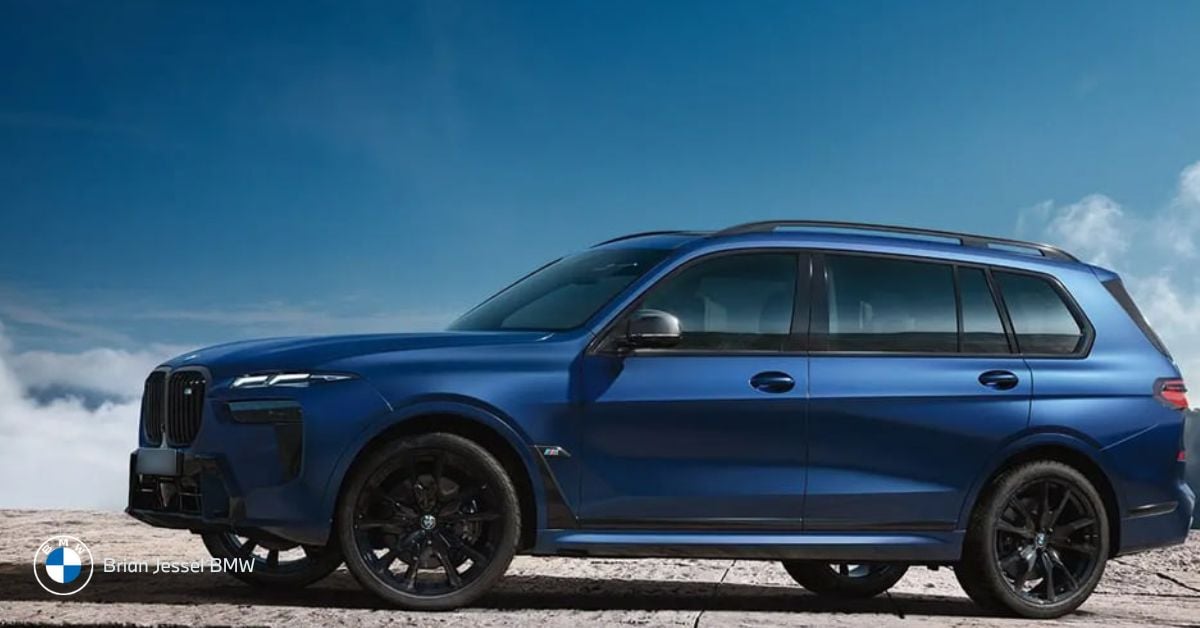 Blue 2023 BMW X7 M60i parked on stone platform under bright sky, showcasing luxury SUV design
