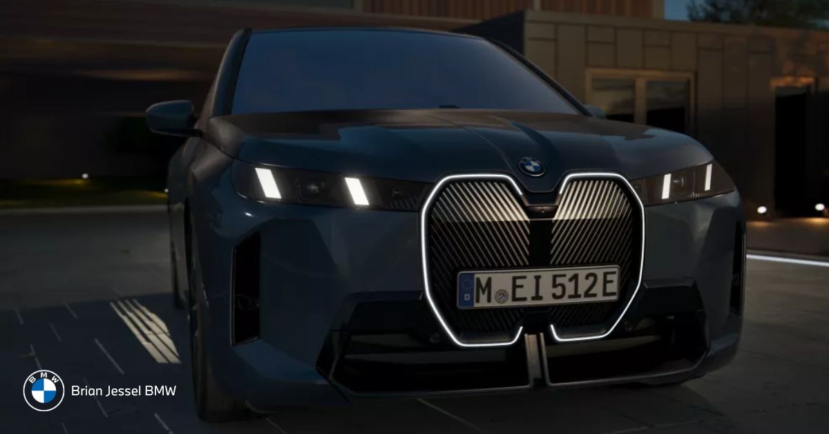 Front view of a dark BMW iX at night showcasing its illuminated grille and modern headlights
