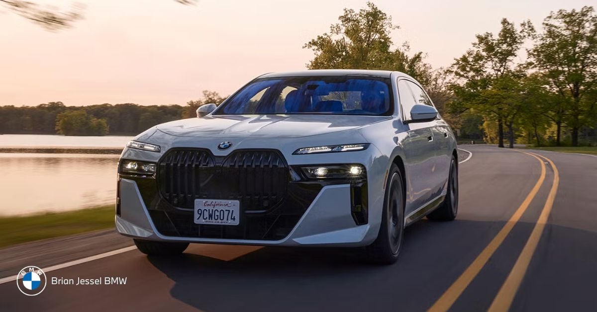 BMW 7 Series full-size luxury sedan driving lakeside road emphasizing upscale comfort and space