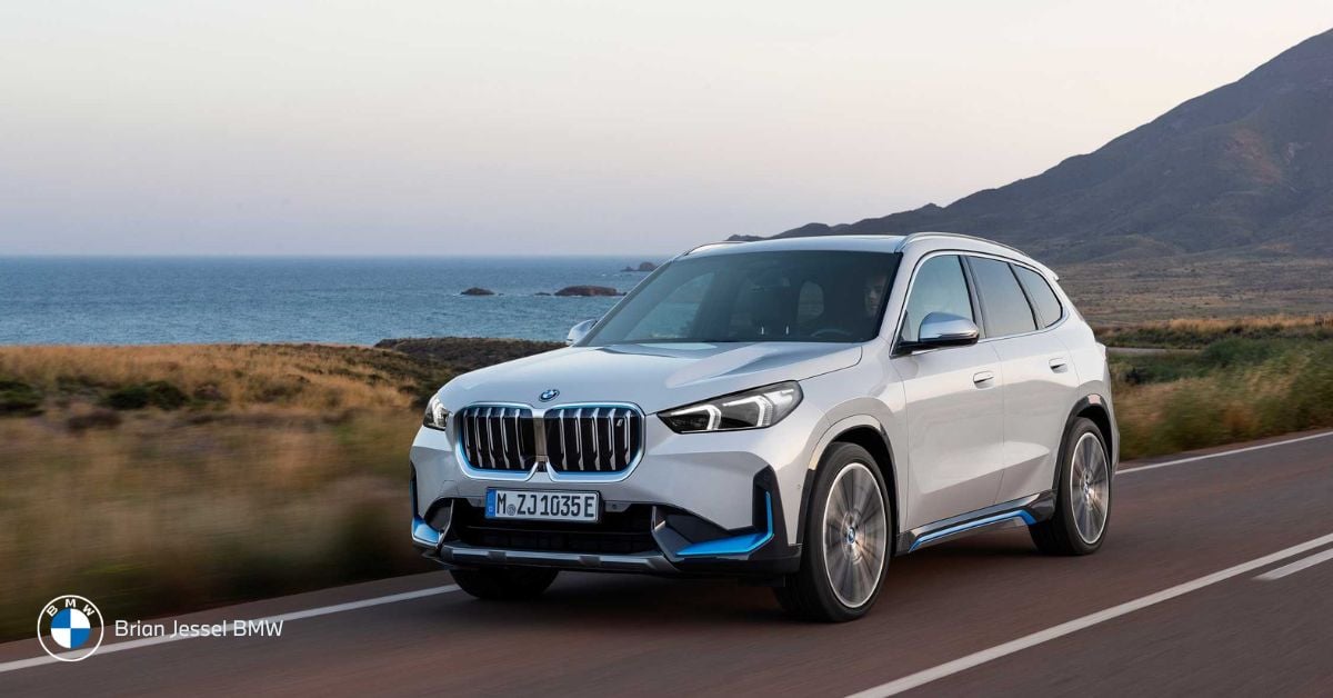White BMW X1 drives along coastal road, showcasing compact size, premium styling, and everyday urban versatility