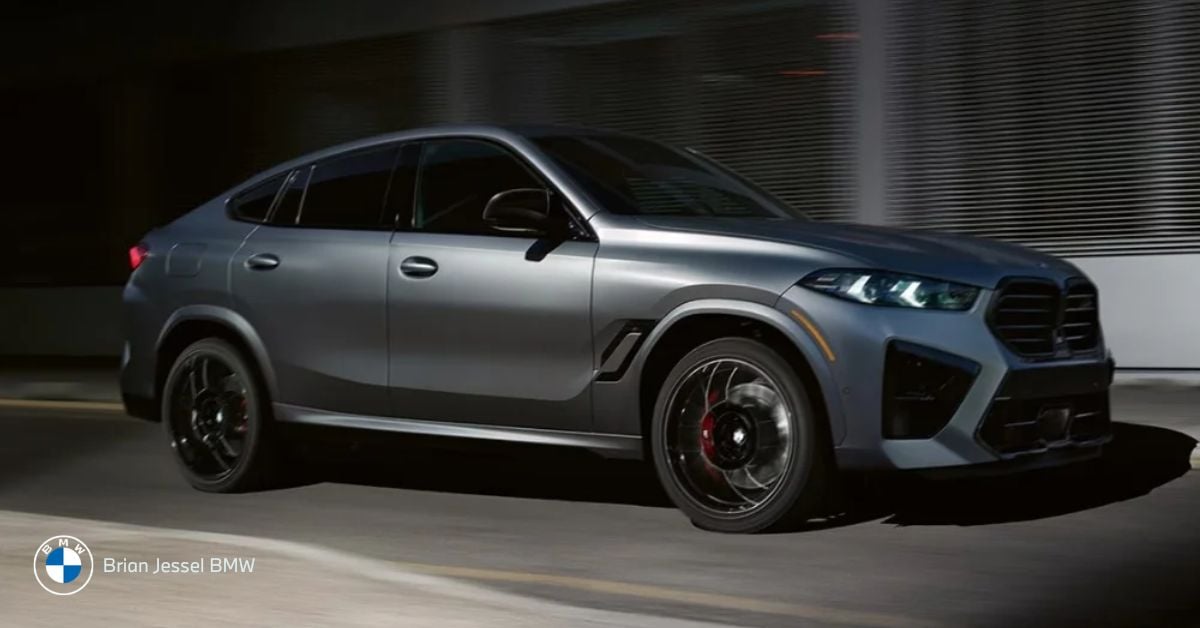 Gray BMW X6 M Competition speeds through city at night, showcasing coupe-style SUV design and performance stance