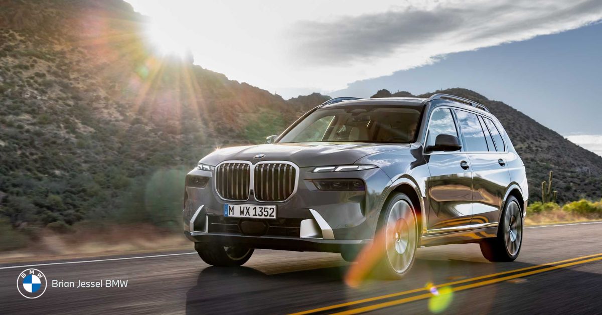 Silver BMW X7 drives along desert highway, showcasing largest BMW SUV with luxury, space, and commanding presence.