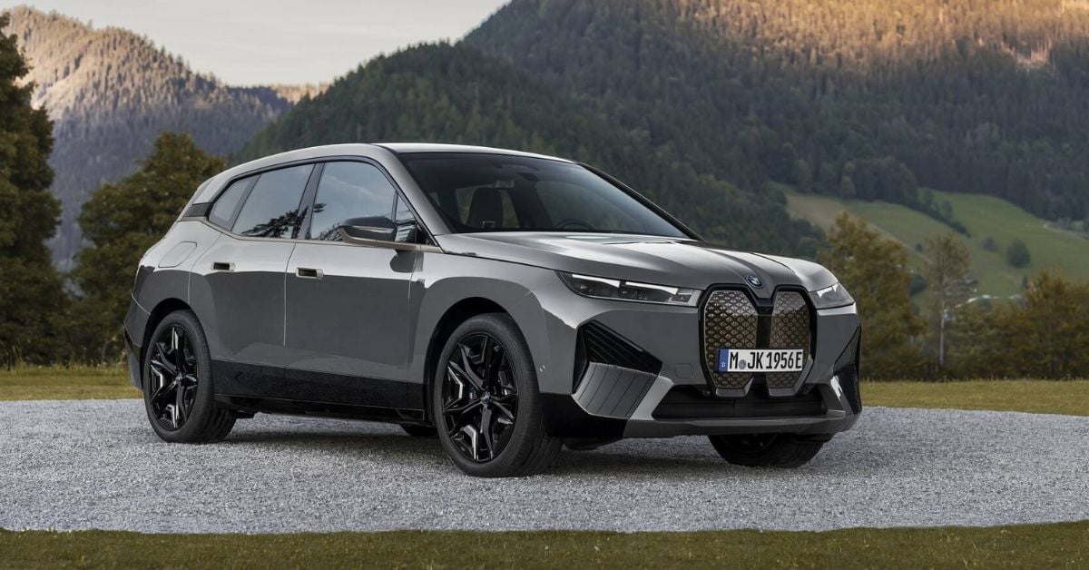 Silver BMW iX M60 electric SUV parked in alpine setting, showcasing premium design and high-performance electric capability