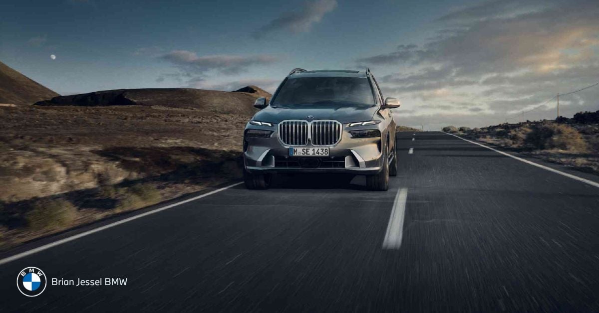 BMW X7 driving on a road in a desert landscape, showcasing its powerful front view