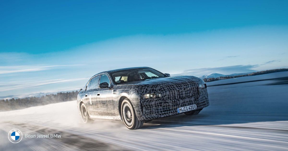 A camouflaged BMW prototype sedan undergoes high-speed testing on a vast, snow-covered track in winter.