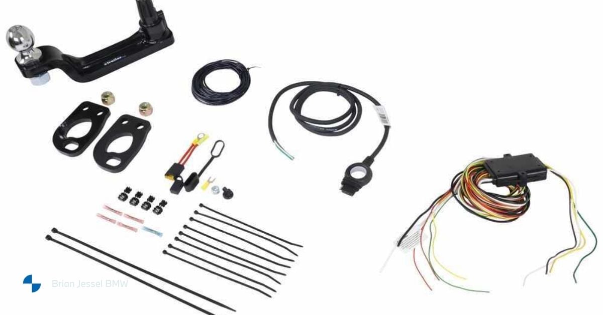 Assorted BMW towing accessories including hitch receiver, wiring harness, connectors, and mounting hardware laid out on white background