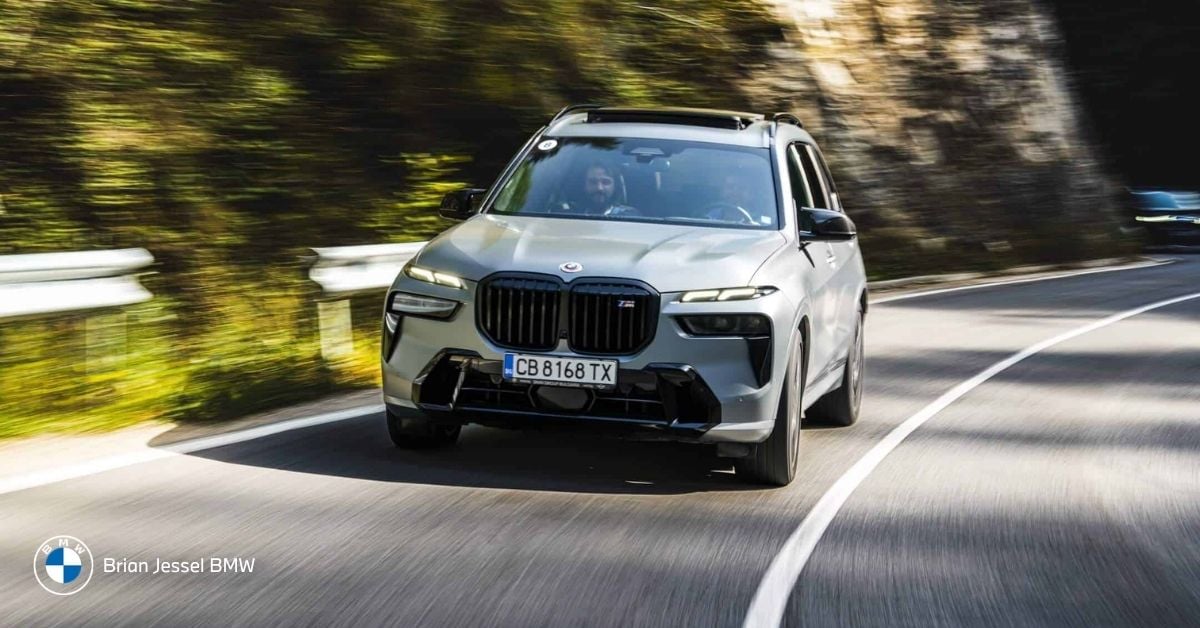 BMW X5 driving dynamically on a winding mountain road with motion blur, ideal for Whistler trips