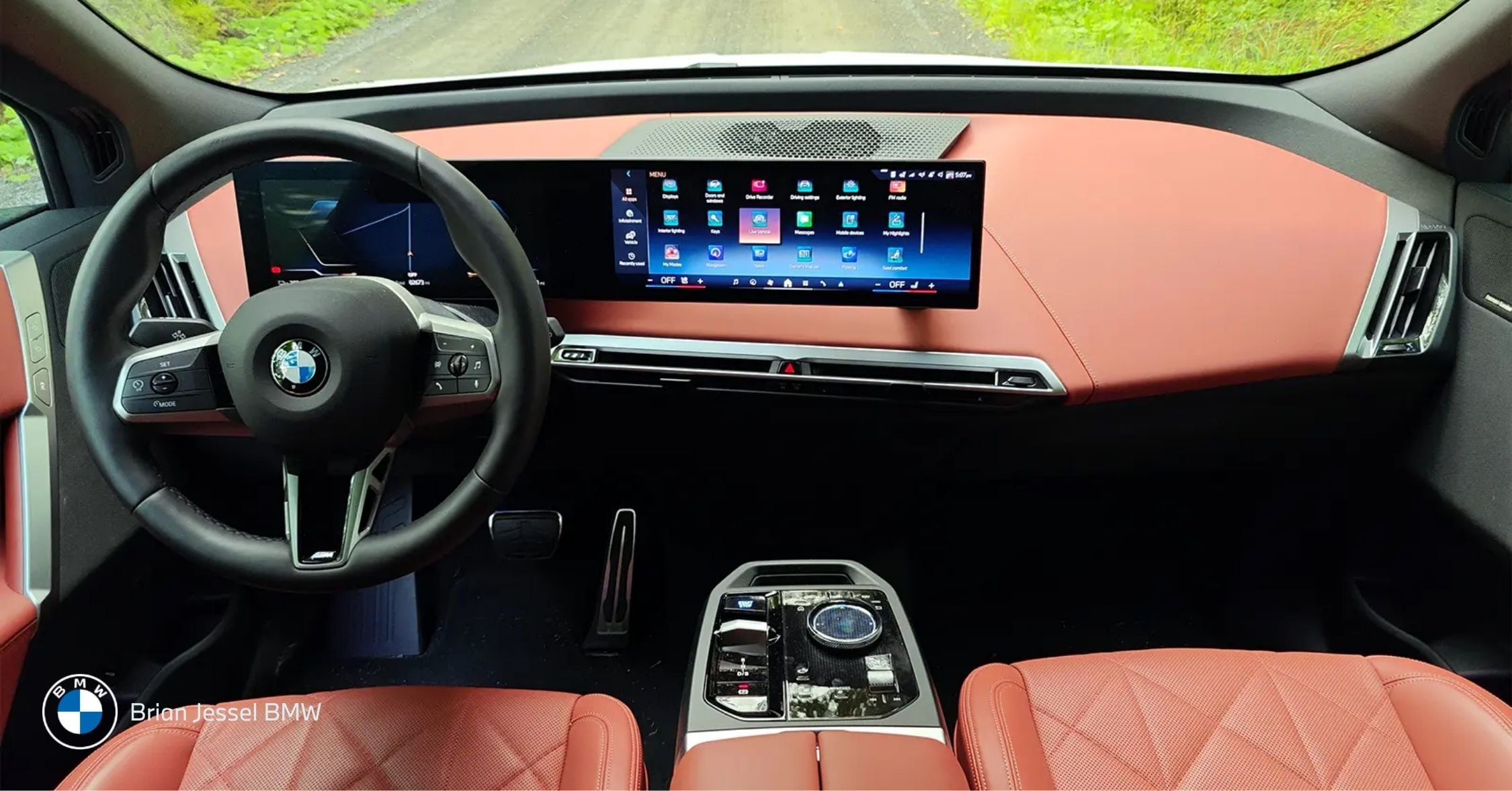 BMW interior with curved digital dashboard displaying driver assistance interface and navigation on a scenic road