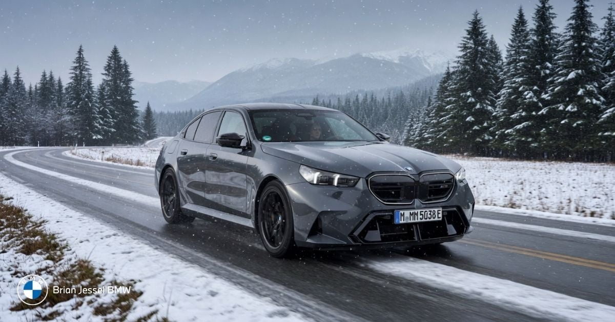 BMW sedan driving on a snowy mountain road surrounded by evergreen trees and distant peaks near Whistler, BC
