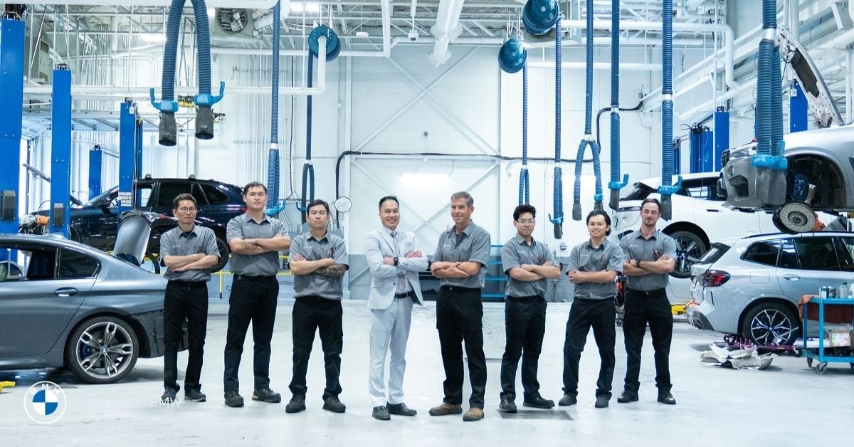 Group of smiling BMW technicians and managers lined up in the bright service bay at Brian Jessel BMW