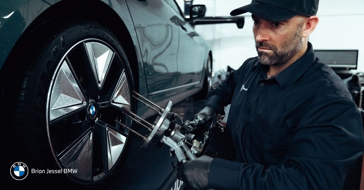 BMW technician performing wheel alignment and tire service to help extend tire life and improve driving stability.