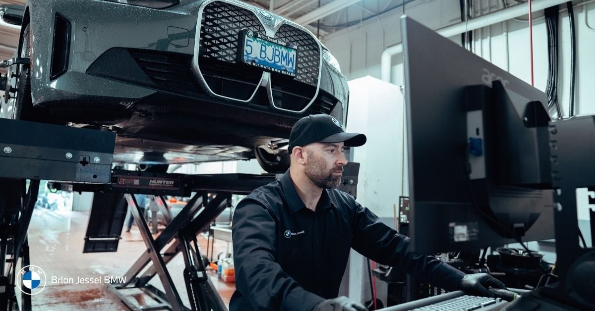 BMW technician inspecting vehicle diagnostics on computer during service, maintaining sensors, software systems, and overall vehicle technology performance