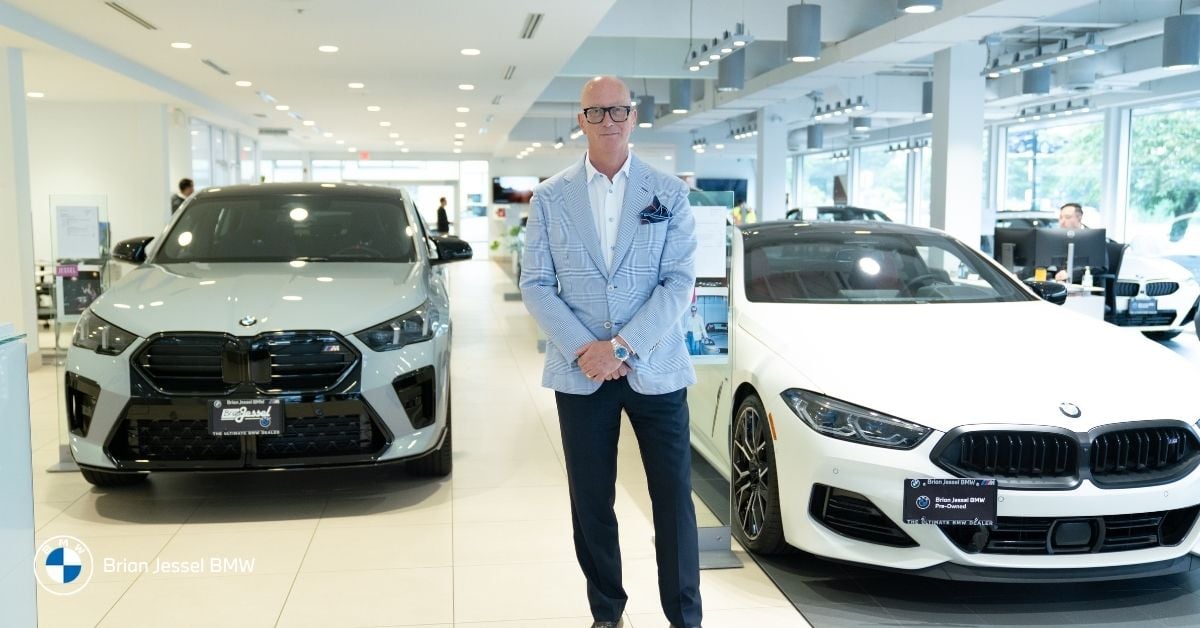 Salesman standing between BMW cars inside Brian Jessel BMW showroom in Vancouver offering i4 and i5 models