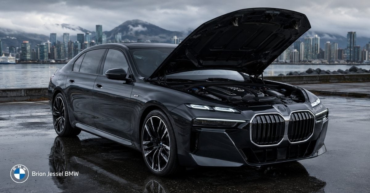 Black BMW sedan with hood open revealing engine by Vancouver waterfront, illustrating why regular oil changes are critical.