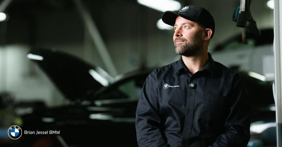 BMW technician in black uniform stands thoughtfully in Brian Jessel BMW service bay during scheduled maintenance