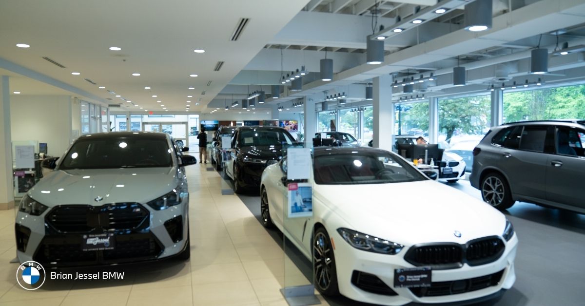 BMW showroom interior displays silver SUV, white coupe and other models under modern lighting with large windows.