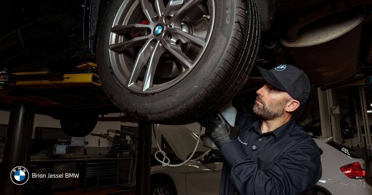 Brian Jessel BMW technician inspects wheel and brake components during professional service in Vancouver workshop.