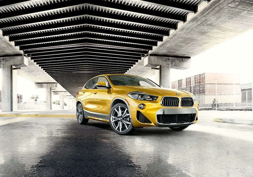 Yellow BMW X2 under an urban overpass