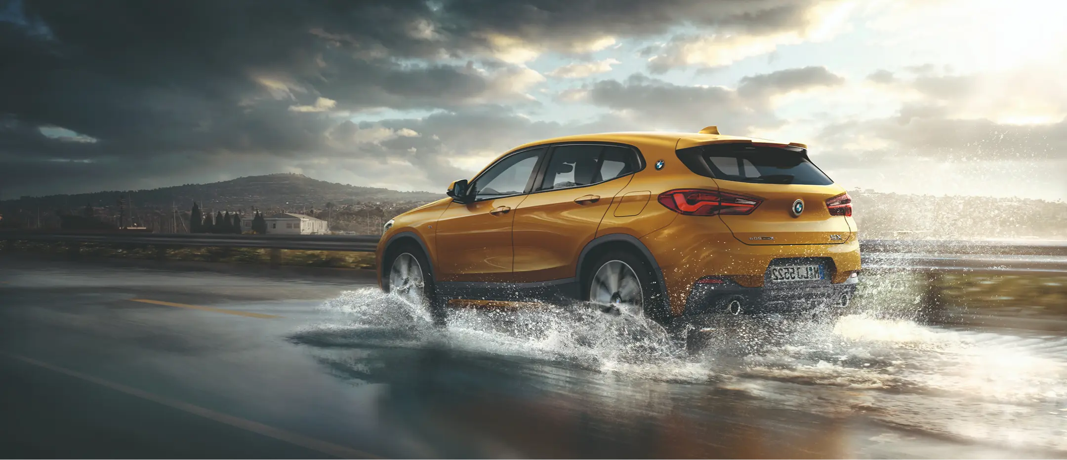 Yellow BMW X2 driving through water