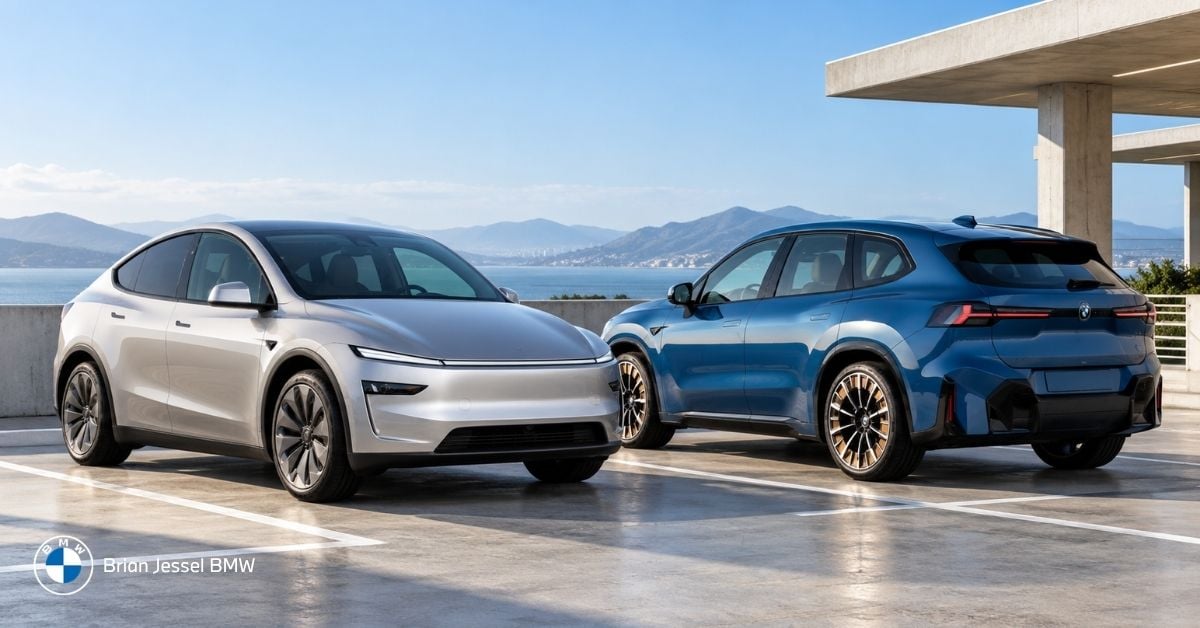 2027 BMW iX3 and Tesla Model Y parked on rooftop overlooking coastal mountains and water.