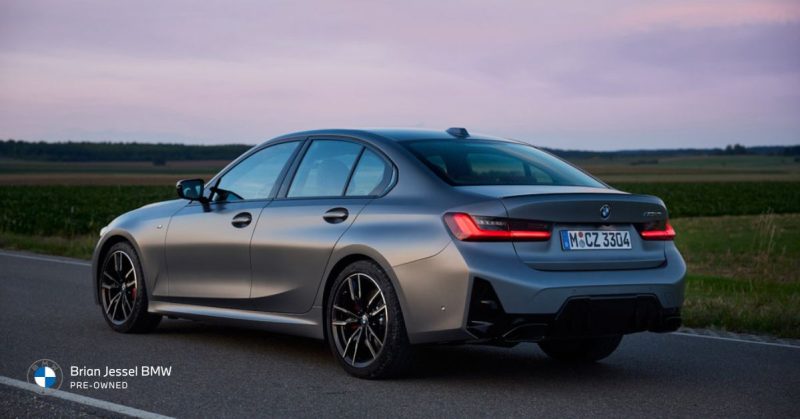 Balanced BMW 3 Series sedan driving on open road at sunset, showcasing sporty rear design and stance