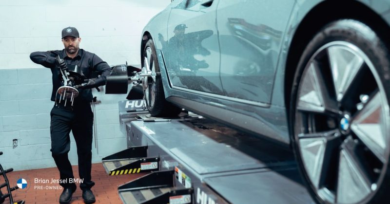 A technician at Brian Jessel BMW performs wheel alignment on a car, highlighting the importance of regular maintenance for long-term vehicle performance.
