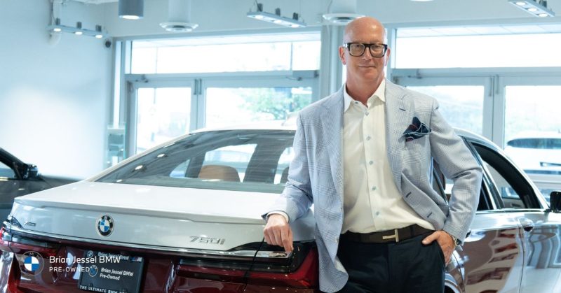  standing next to a BMW 750i, showcasing luxury vehicle shopping
