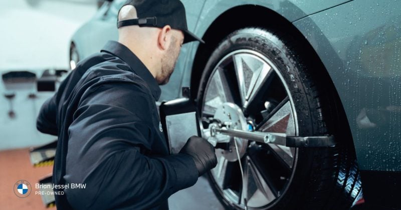 BMW technician performing wheel alignment on an EV, ensuring optimal performance and longevity of the vehicle