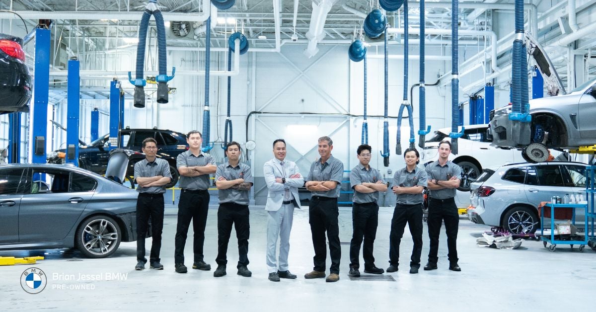Team at Brian Jessel BMW Pre-Owned standing proudly in a well-equipped service center with BMW vehicles