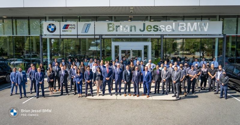 A group photo of the Brian Jessel BMW Pre-Owned team in front of their dealership
