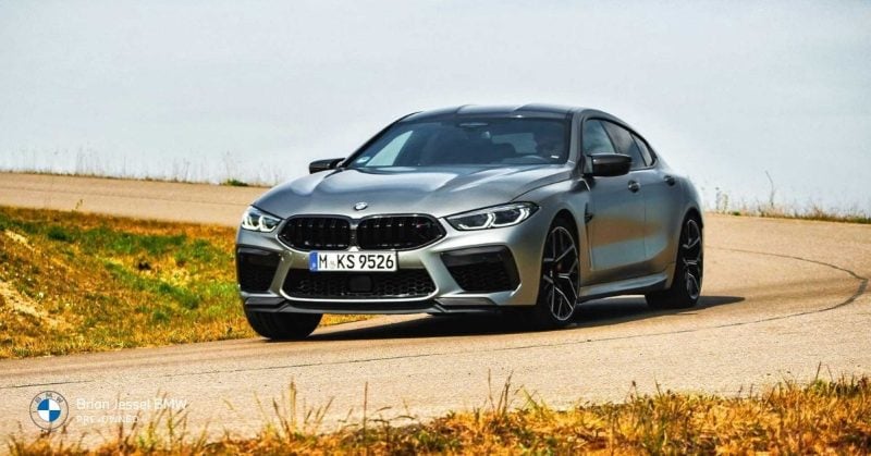 2020 BMW M8 Competition Coupe driving on open road, showcasing aggressive front design, stability, and high performance dynamics