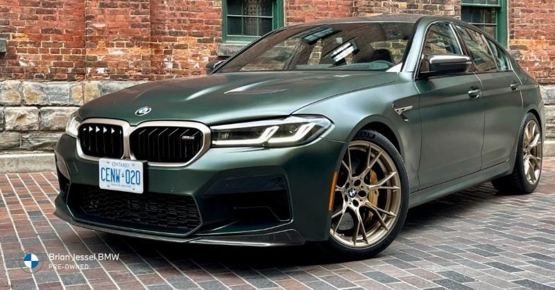 2022 BMW M5 CS green performance sedan parked on brick street showcasing aggressive front design and wheels