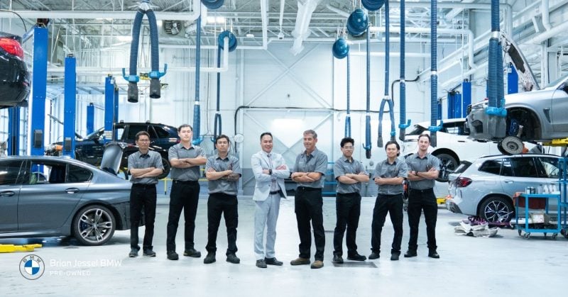 Professional BMW technicians and manager posing together in the bright Brian Jessel BMW service workshop in Vancouver