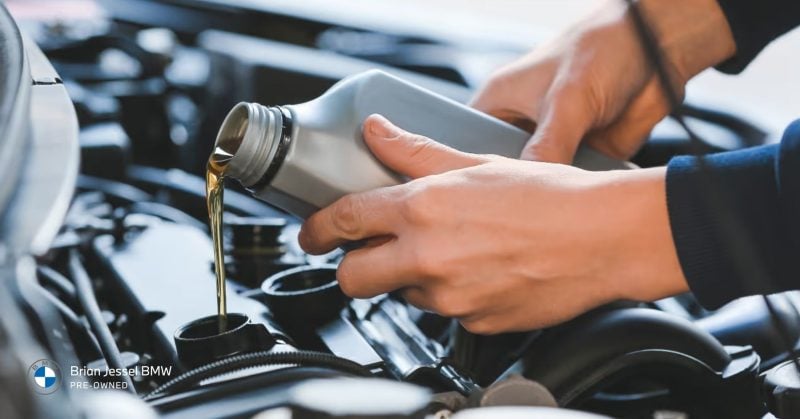 Mechanic pouring fresh oil into a BMW engine during routine service in Vancouver
