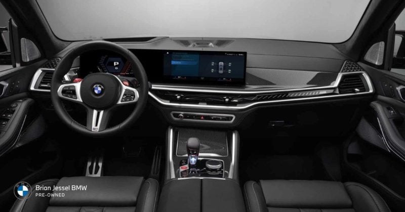 Luxurious black leather interior of a BMW SUV showing modern dashboard, large digital displays, and steering wheel