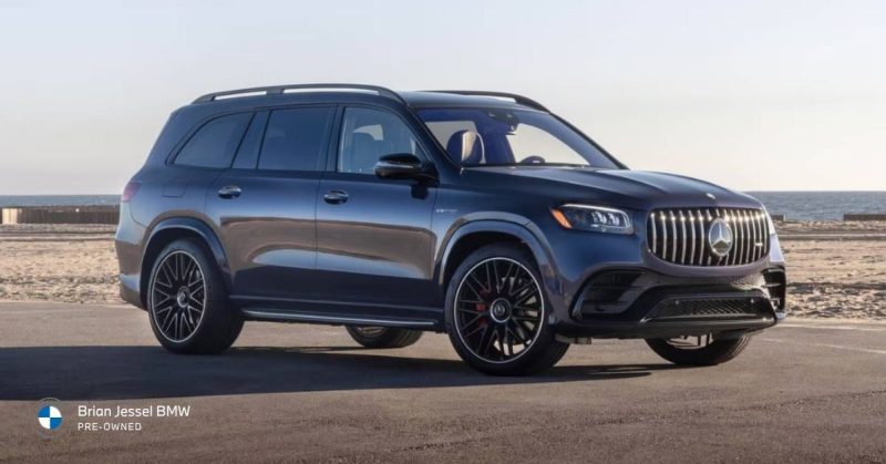Dark blue luxury SUV parked on a paved lot with ocean and beach visible in the background