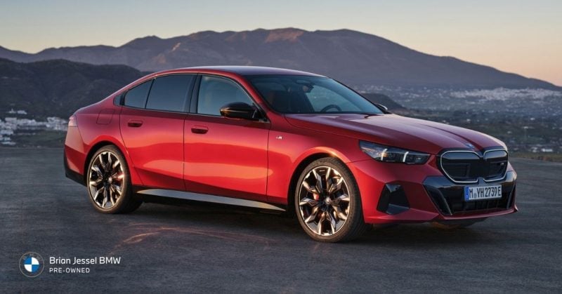 Red BMW 5 Series luxury sedan parked at sunset, showcasing spacious comfort and refined long-distance driving performance daily.