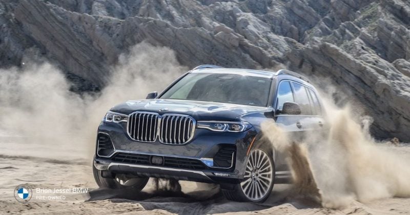 BMW X7 SUV driving through rugged terrain, highlighting spacious comfort, family travel capability, and long-distance driving stability