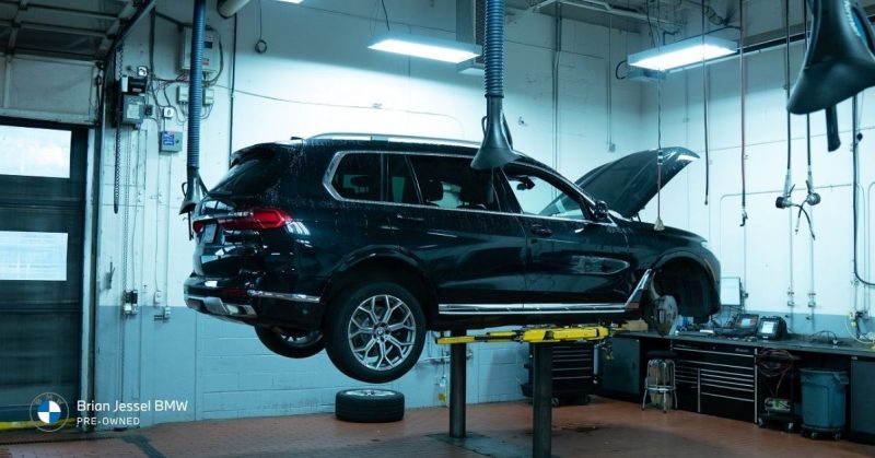 Black BMW SUV elevated in service garage during inspection, representing maintenance issues, repairs, and long-term engine lifespan concerns.