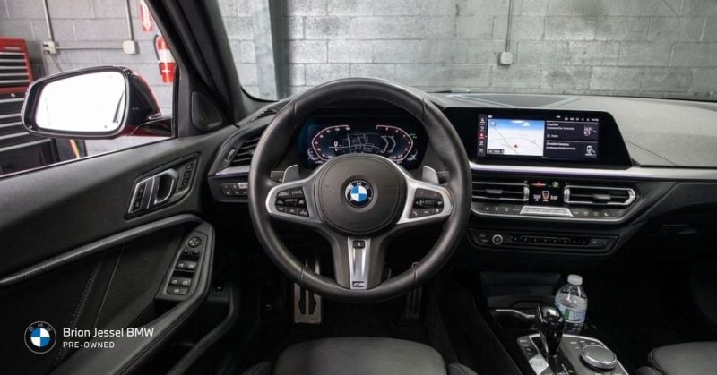 BMW dashboard and steering wheel inside modern used vehicle, highlighting navigation screen, controls, and clean interior condition.