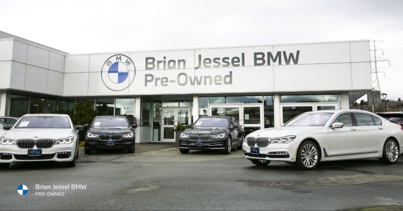 Exterior view of Brian Jessel BMW Pre-Owned dealership featuring multiple luxury BMW sedans displayed outside Vancouver showroom location.