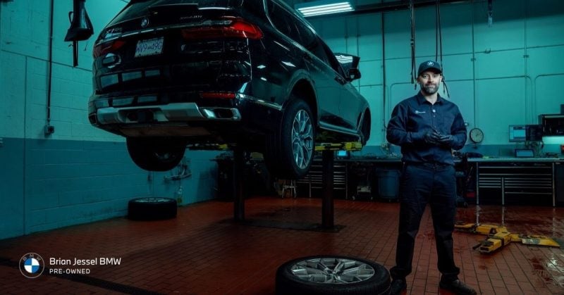 BMW technician servicing elevated BMW SUV inside Vancouver workshop, highlighting specialized diagnostics, repairs, and certified maintenance expertise services.