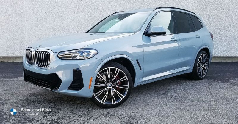 Light blue BMW X3 SUV parked on asphalt in front of a textured wall at Brian Jessel BMW dealership