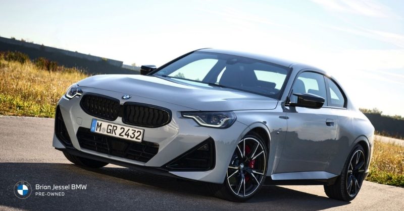 Silver BMW 2 Series Coupe parked on a scenic road, highlighting its sleek sporty design and aggressive front styling