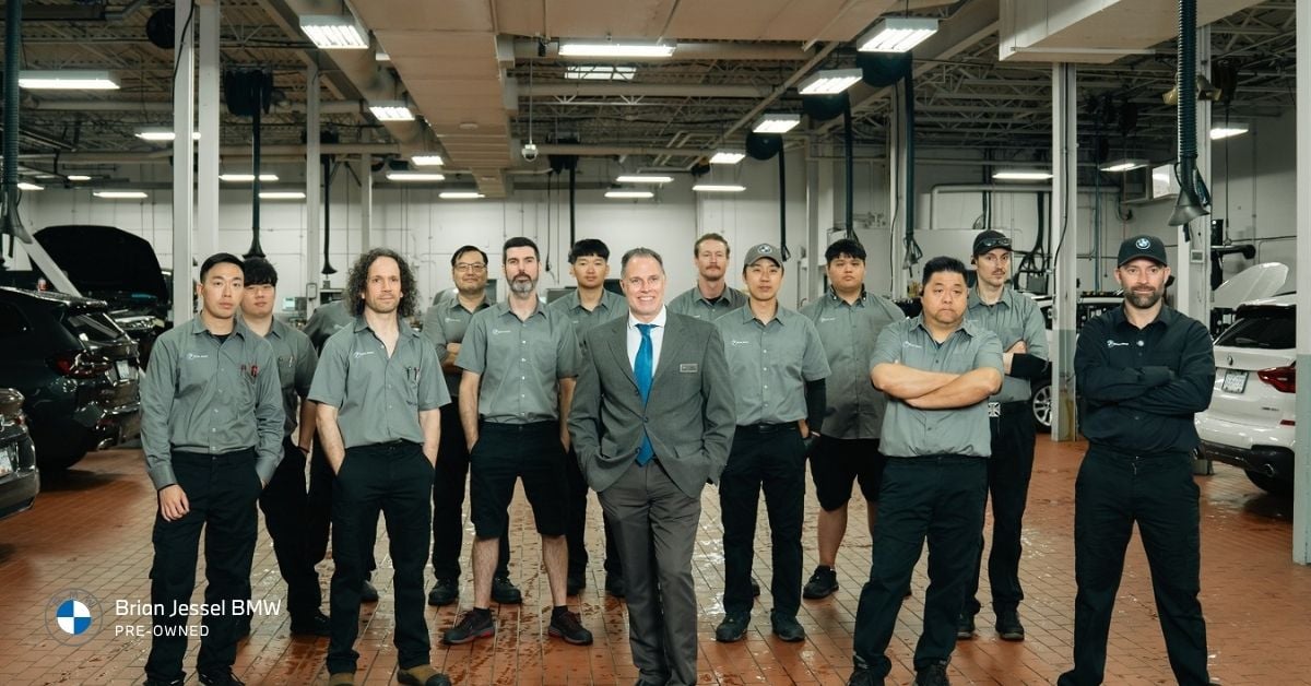 Brian Jessel BMW service team standing together inside workshop with technicians and professional automotive facility.
