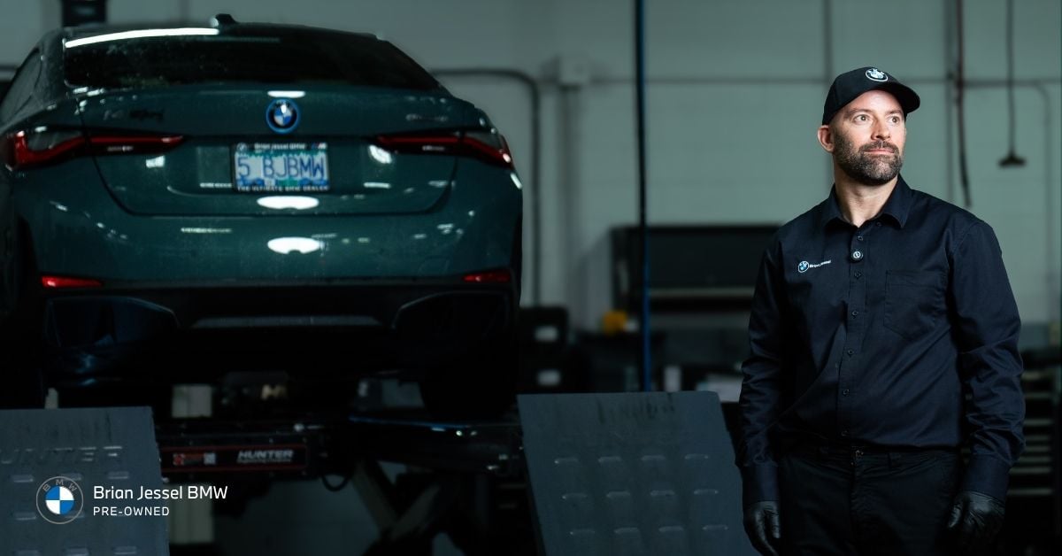 BMW certified technician stands beside a BMW vehicle during service at Brian Jessel BMW Pre-Owned.