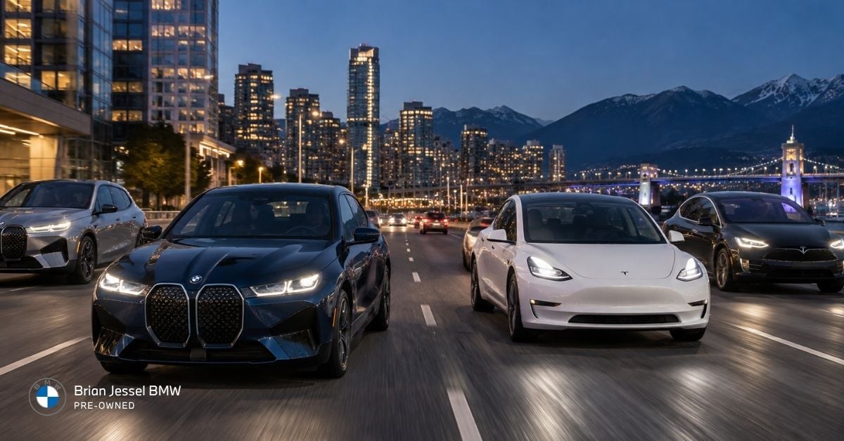 BMW and Tesla electric vehicles driving through Vancouver streets at dusk with skyline and mountains.